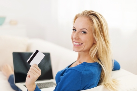 Beautiful woman sitting on sofa with laptop and credit card 
の写真素材