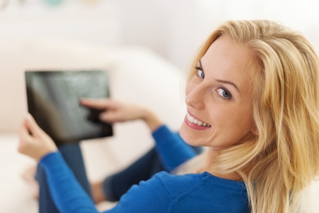 Relaxed woman sitting on sofa with digital tablet の写真素材