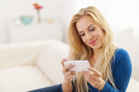 Beautiful woman with white mobile phone at living room の写真素材