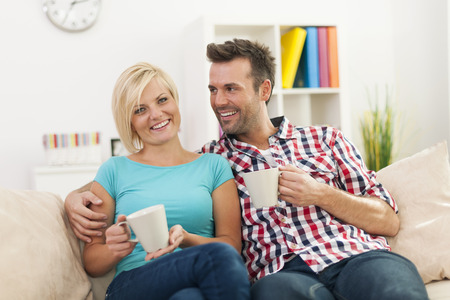 Beautiful couple relaxing on sofa with cup of coffee の写真素材
