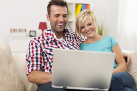 Excited couple looking on laptop at home の写真素材