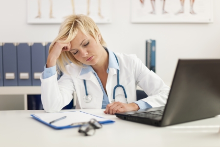 Exhausted female doctor in office の写真素材