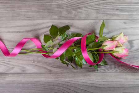 Bouquet of pink roses wrapped in ribbon on wood の写真素材