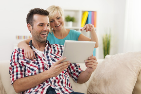 Happy couple using digital tablet at home の写真素材