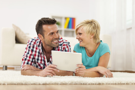 Loving couple with digital tablet on carpet の写真素材