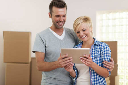 Happy couple using digital tablet during the moving homeの写真素材
