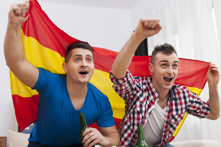 Men watching football match on TV and cheering of spanish team の写真素材