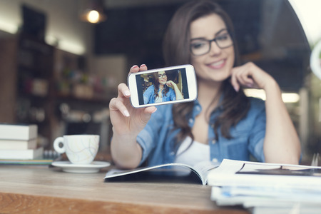 Attractive woman taking self portrait by mobile phone の写真素材