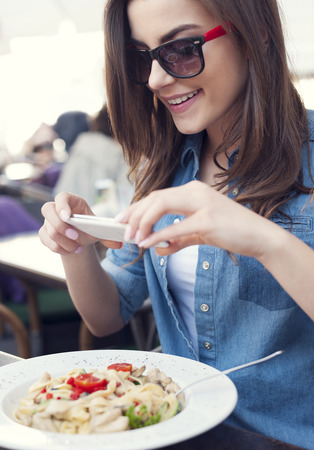 Hipster woman taking a picture of italian meal の写真素材