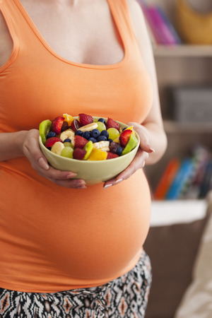 Close up of pregnant woman with fruit saladの写真素材