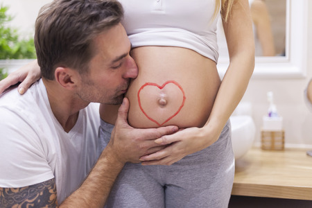 Man kissing his womans bellyの写真素材