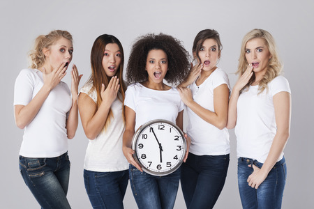 Multi ethnic shocked women with clockの写真素材