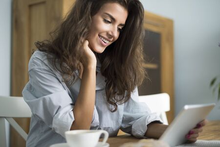 Woman browsing her digital tablet in the morning