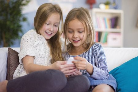 Two girls reading funny message from friendの写真素材
