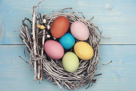 Bird nest fulfilled with pastel color eggs