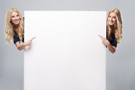 Adult girls pointing at blank placardの写真素材