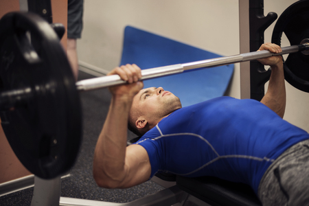 Focused man doing workout on weight benchの写真素材
