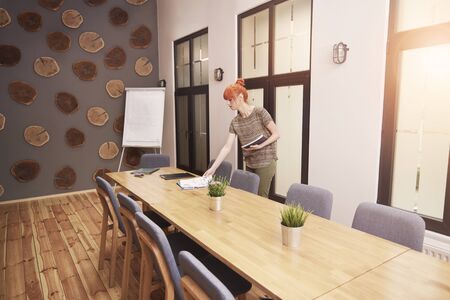 Young woman preparing the boardroom for conference