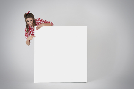 Pin up girl pointing a white placardの写真素材