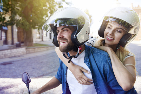 Couple in helmets riding a scooterの写真素材