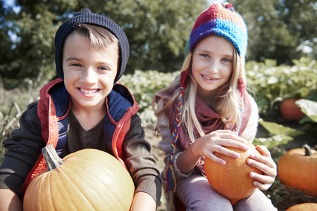 Boy and girl on pumpkin fieldの写真素材