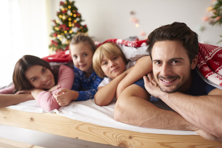 Family lying in bed at Christmas timeの写真素材