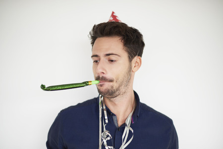 Dark haired man with party horn blowerの写真素材