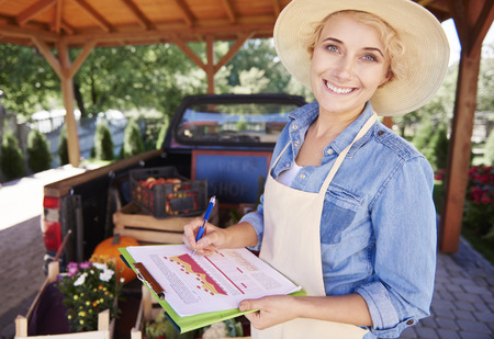 Smiling woman with clipboard in greenhouse