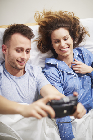 Young couple taking pictures on bedの写真素材