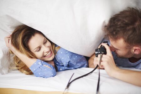 Man taking photos under blanket to her girlfriendの写真素材
