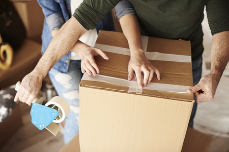 Couple packing cardboard boxes with adhesive tape の写真素材