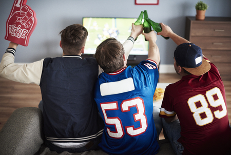 Toasting men while watching matchの写真素材