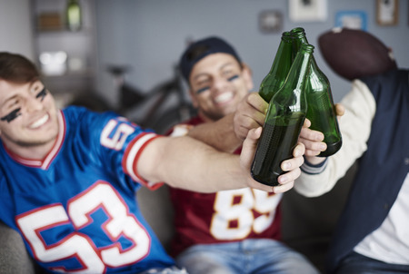 American football fans make a toast indoorsの写真素材
