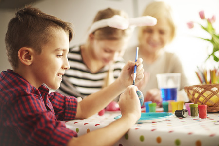 Little boy painting Easter eggs by paintbrushの写真素材