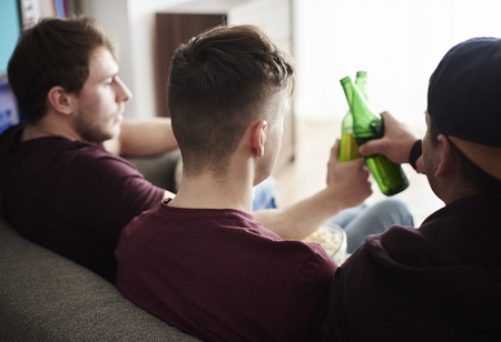 Rear view of three guys toastingの写真素材