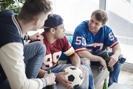 Friends seated on a sofa and watching soccer gameの写真素材