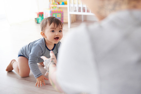 Mother watching baby son crawl towards herの写真素材