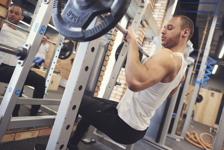 Motivated young man lifting barbell