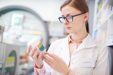 Pharmacist reviewing medicine label on bottleの写真素材