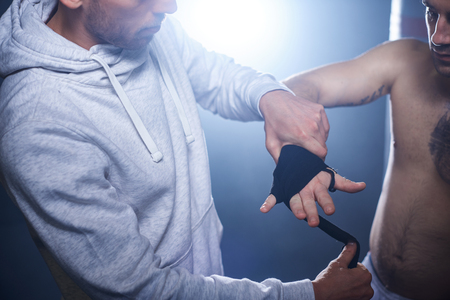 Trainer wrapping hand of male boxerの写真素材