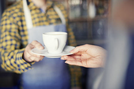 Waiter giving cup of coffee to customerの写真素材