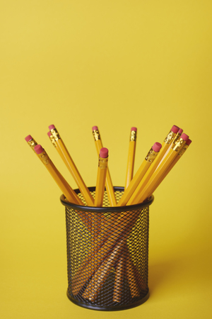 Pencils in desk organizer against yellow backgroundの写真素材