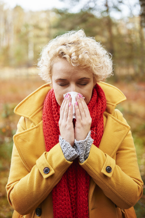 Picture of sneezing woman with tissue in handsの写真素材