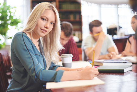 Woman studying in library with another studentsの写真素材