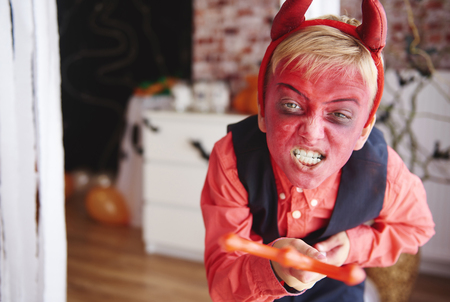 Boy in devil costume trying to scare peopleの写真素材