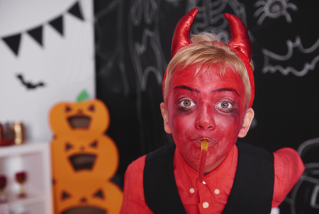 Boy in devil costume with gummy wormの写真素材