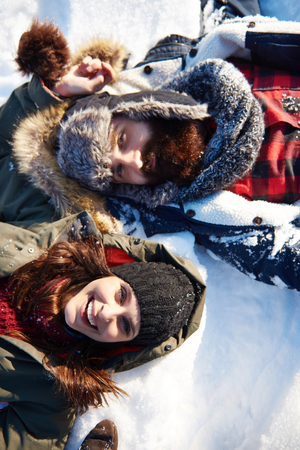Couple lying on the white snowの写真素材