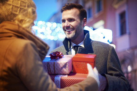 Mature man receiving full of presents from  womanの写真素材