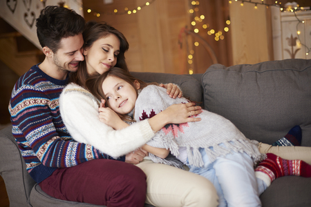 Happy parents with girl relaxing on the sofa の写真素材