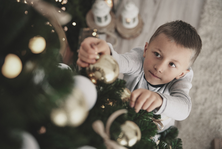 Boy hanging a christmas ornaments on christmas treeの写真素材